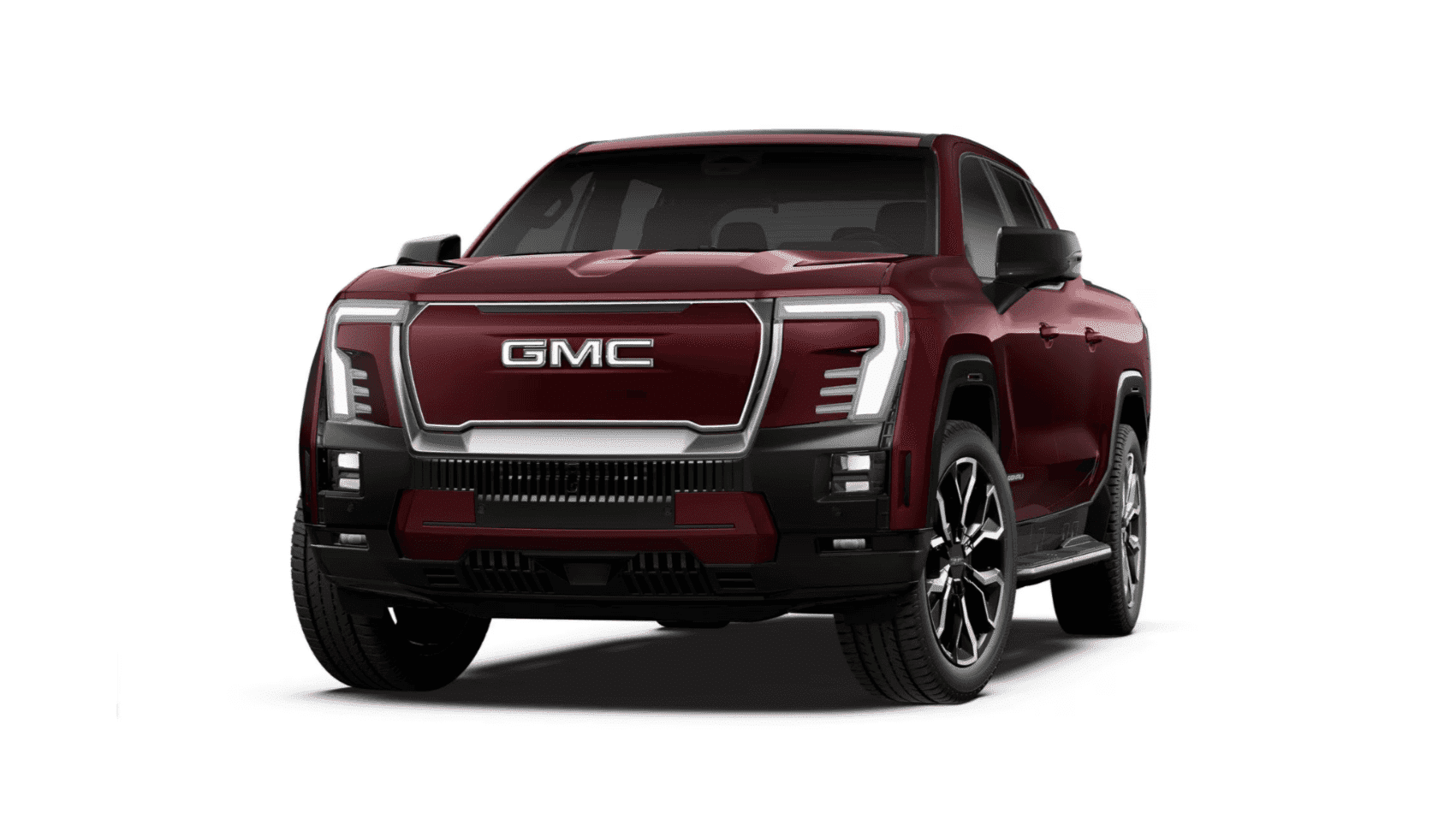 A GMC pickup truck parked on a hillside during sunset, showcasing its modern design, bold front grille, and advanced lighting features against a scenic backdrop of mountains and valleys.