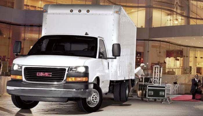 Black GMC truck parked in front of a modern building, showcasing its bold design and sleek exterior features. Ideal for those seeking a combination of style and rugged performance.