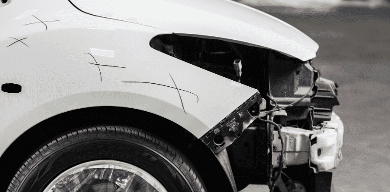 Damaged white car fender with visible scratches and markings indicating repair areas, showcasing the vehicle's need for bodywork and restoration.