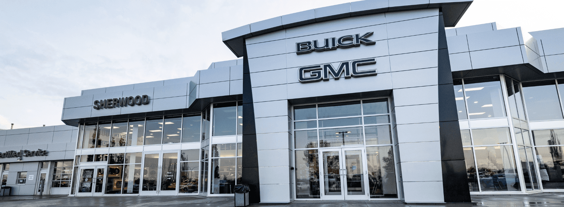 Sherwood Buick GMC dealership exterior showcasing modern architecture and large glass entrance, promoting vehicle sales and customer service.