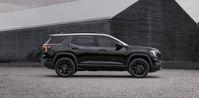 Side view of a modern SUV parked along a scenic lakeside, showcasing its sleek design, contemporary body color, and all-terrain tires, surrounded by greenery and a tranquil landscape in the background.