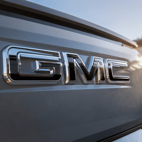 GMC electric truck towing an Airstream trailer on a scenic mountain road, showcasing outdoor adventure and modern vehicle capabilities.
