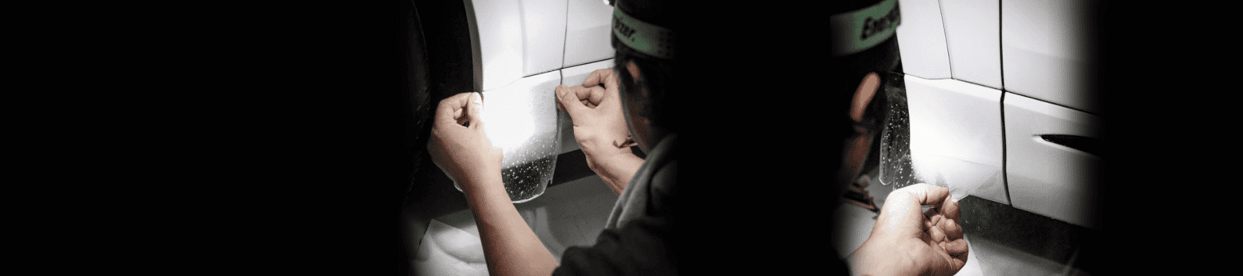 Technician applying a paint protection film on a vehicle's body, focusing on the precise placement and detailing process to ensure optimal protection and finish.