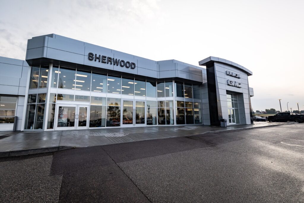 Exterior view of Sherwood Buick GMC dealership showcasing a modern building design with large glass windows and a prominent entrance, emphasizing vehicle sales and customer service.
