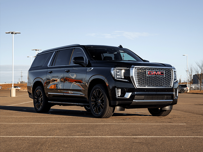 Black GMC SUV parked in an outdoor lot, showcasing its sleek design, chrome grille, and stylish black wheels under clear skies. Ideal for families and adventure seekers, this vehicle combines luxury and functionality.